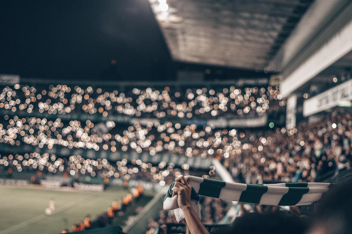 A photo showing fans with painted faces and colorful flags in a stadium, representing the passion and excitement of football rivalries.